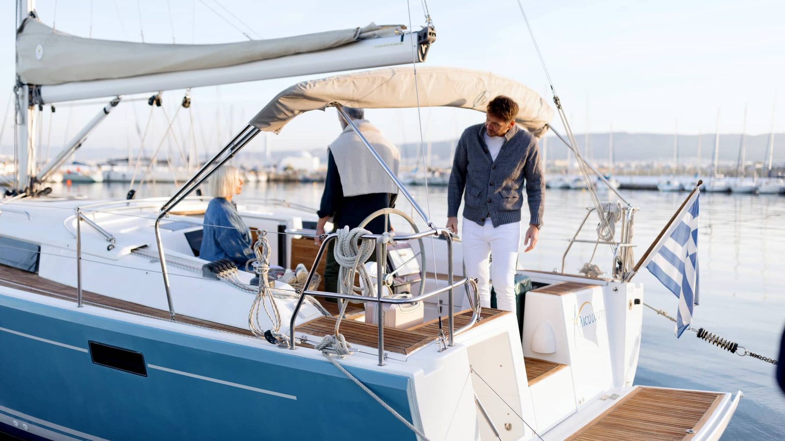 Skipper welcoming guests aboard a crewed sailing yacht in a Greek marina