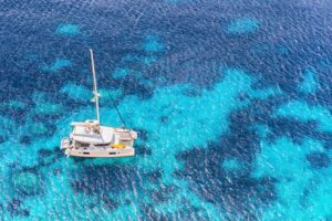 Charter catamaran at anchor in turquoise water, seen from above