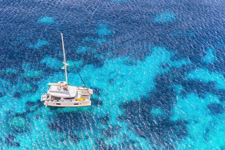 Charter catamaran at anchor in turquoise water, seen from above