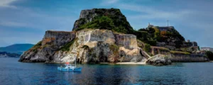 The Old Fortress of Corfu Town seen from the sea, with a small boat at anchor below its cliffs