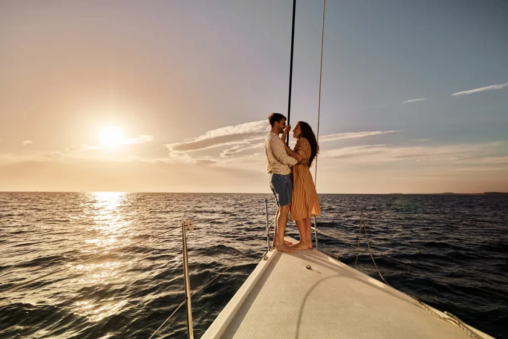 A couple on the bow of a sailing yacht at sunset