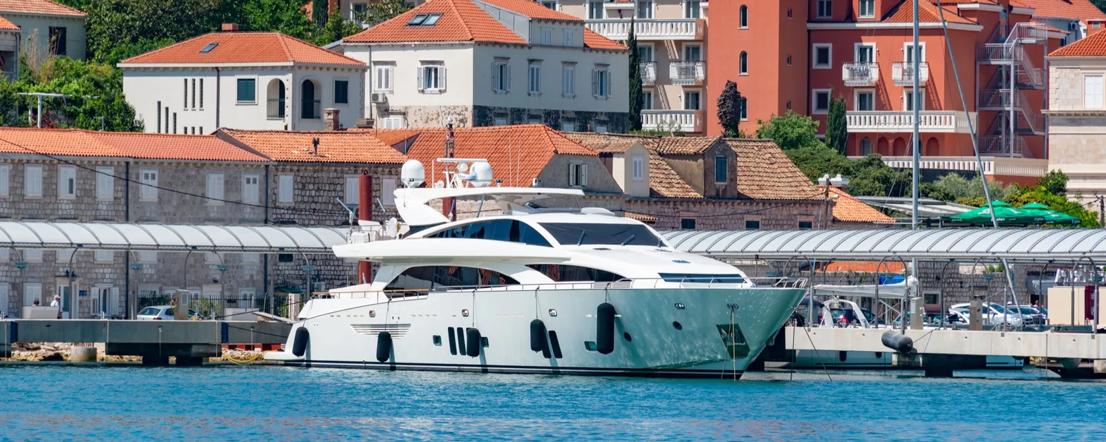 Motor yacht moored on a town quay in front of stone houses with red-tiled roofs