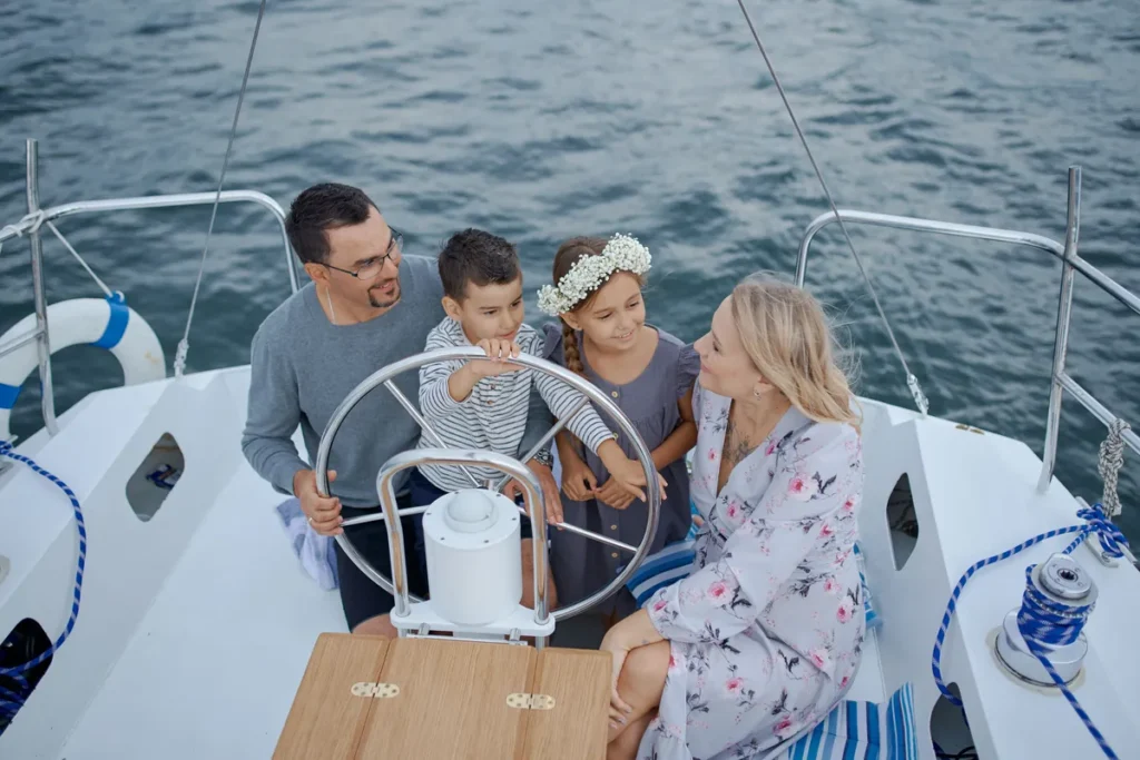 A family with two children at the wheel of a sailing yacht