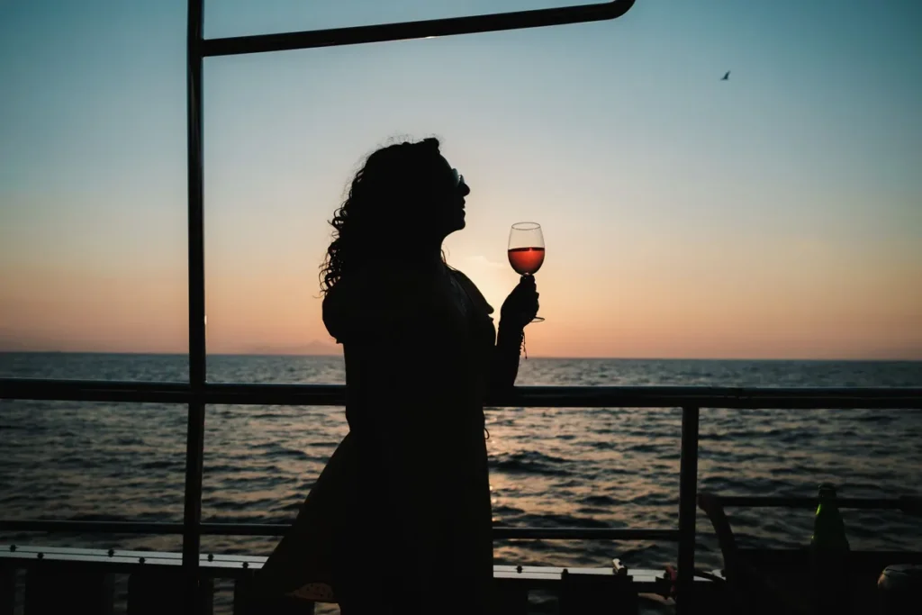 Silhouette of a woman with a glass of rosé on deck at sunset