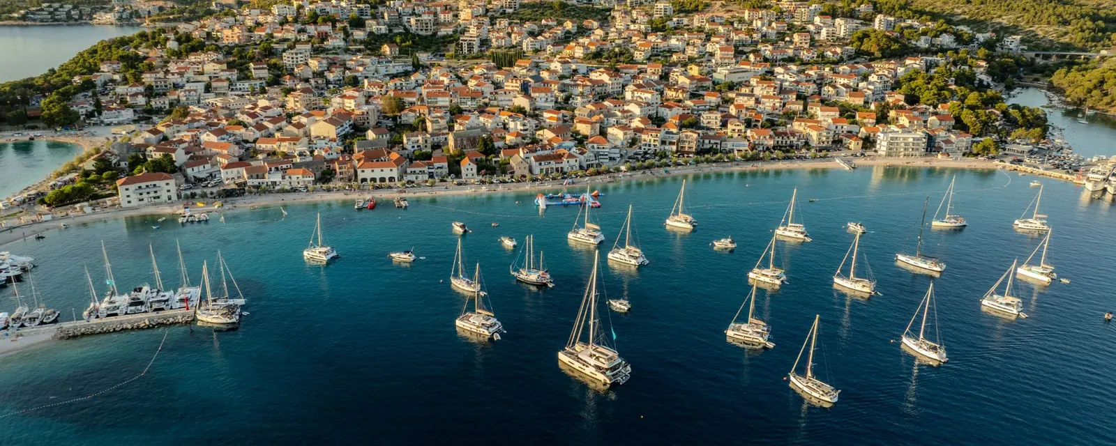 Sailing yachts and catamarans anchored in a bay off a coastal town in Dalmatia, Croatia
