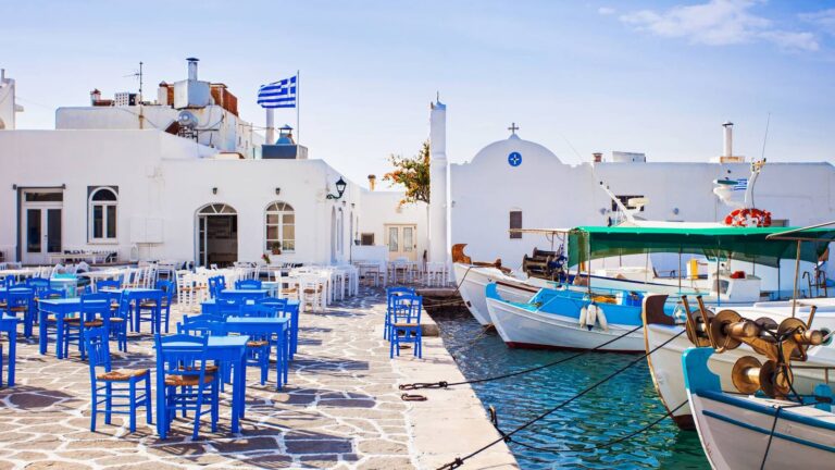 Blue taverna tables and fishing boats in Naoussa harbour, Paros